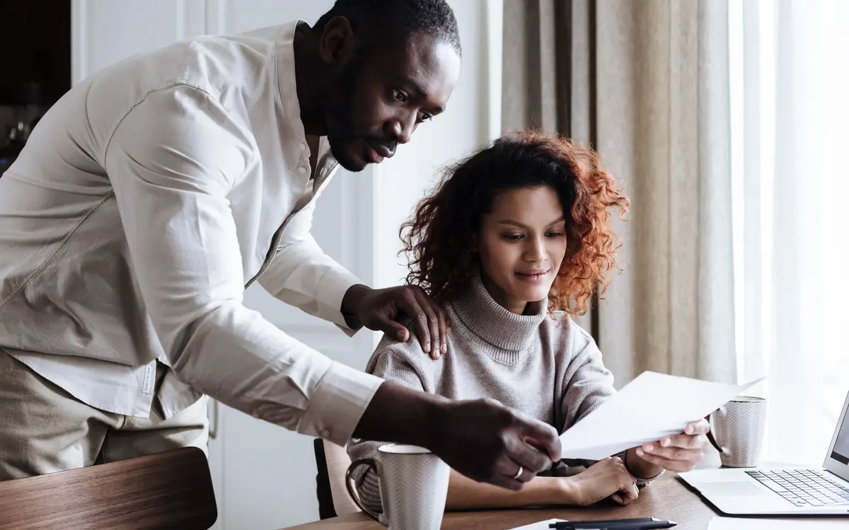 A couple reviewing paperwork with a laptop at home