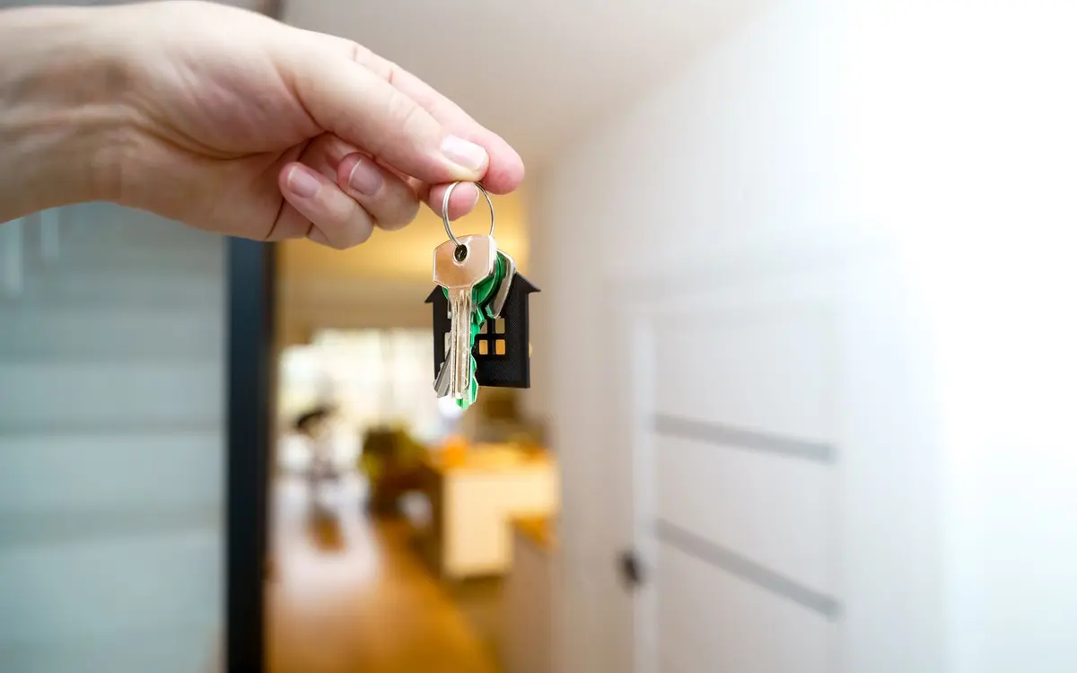 A hand holding house keys inside a home
